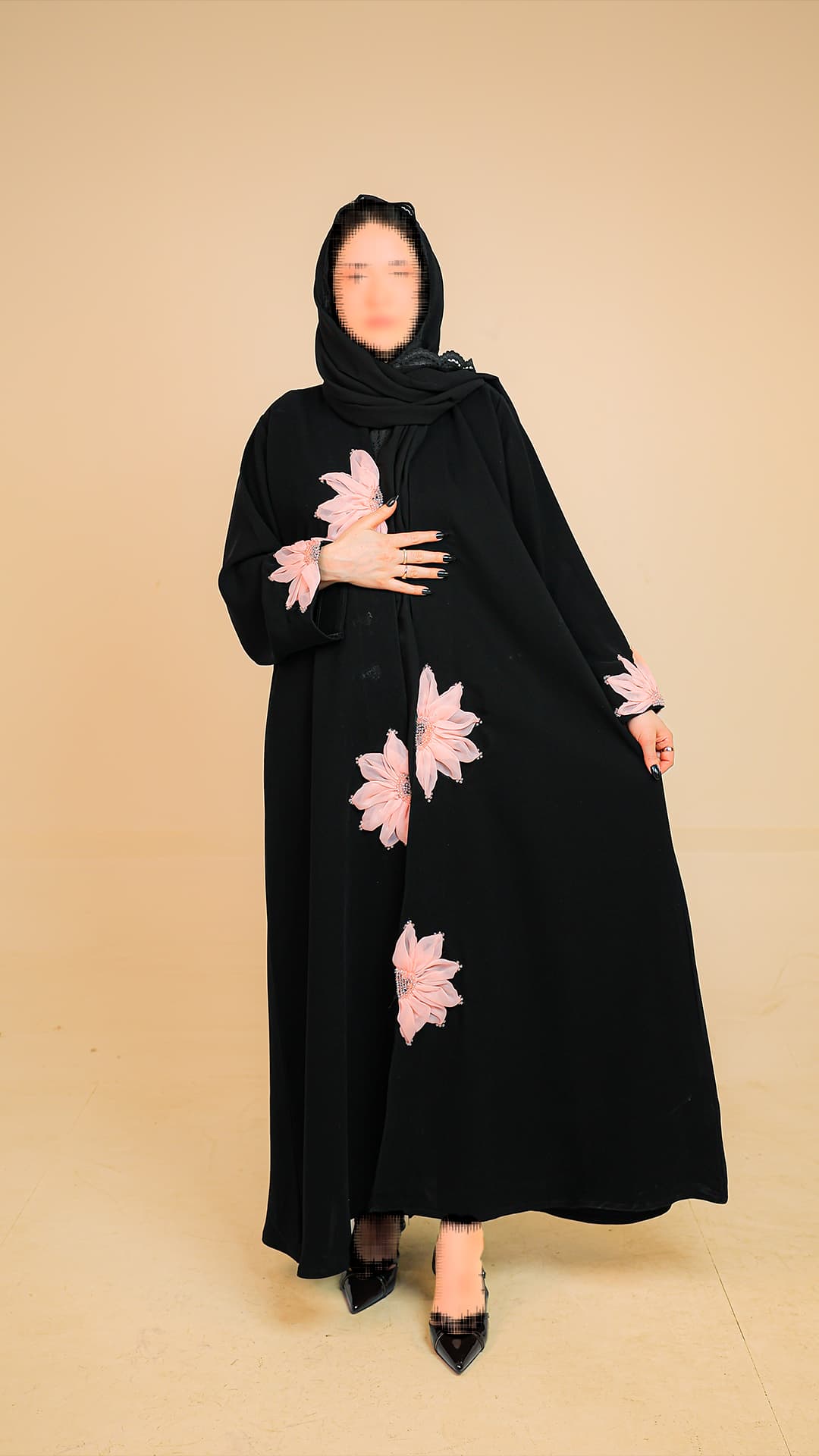 Original product photography for Rilam showing a black abaya with pink floral embroidery against a studio background.