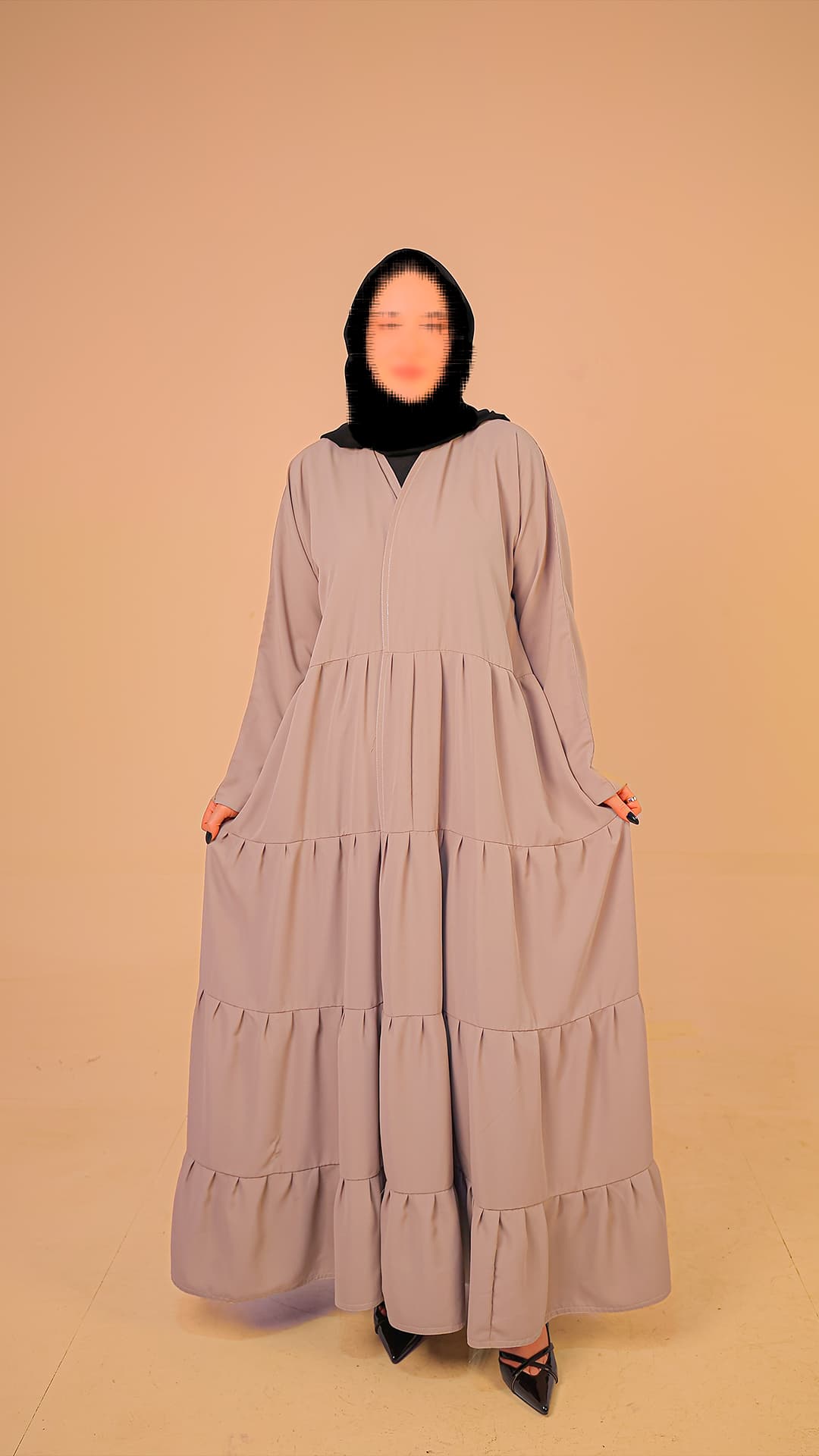Original product photography for Rilam showing a light grey tiered abaya against a plain studio background.