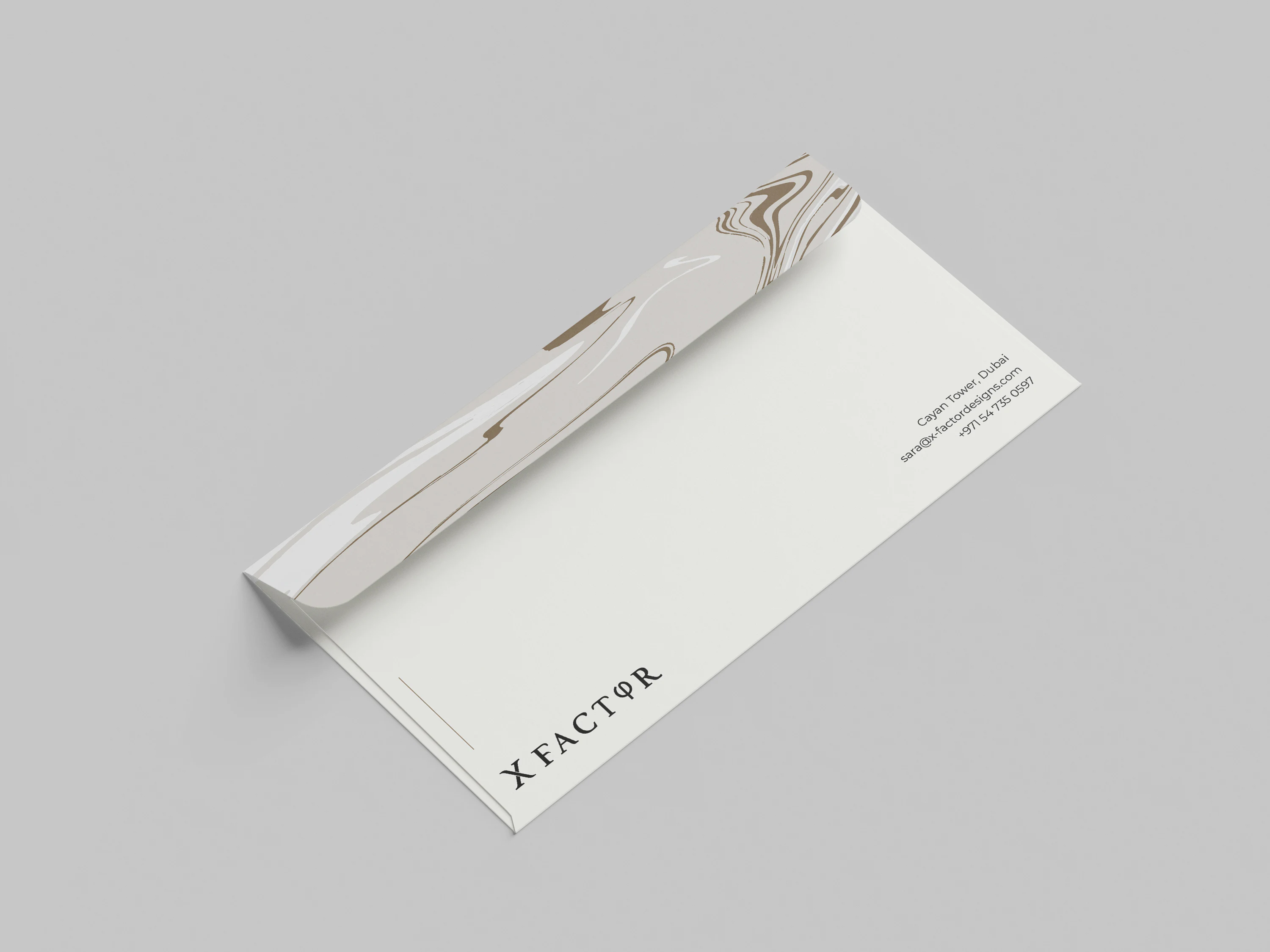 X Factor Interior Design branded DL envelope front mockup with logo and Dubai contact details